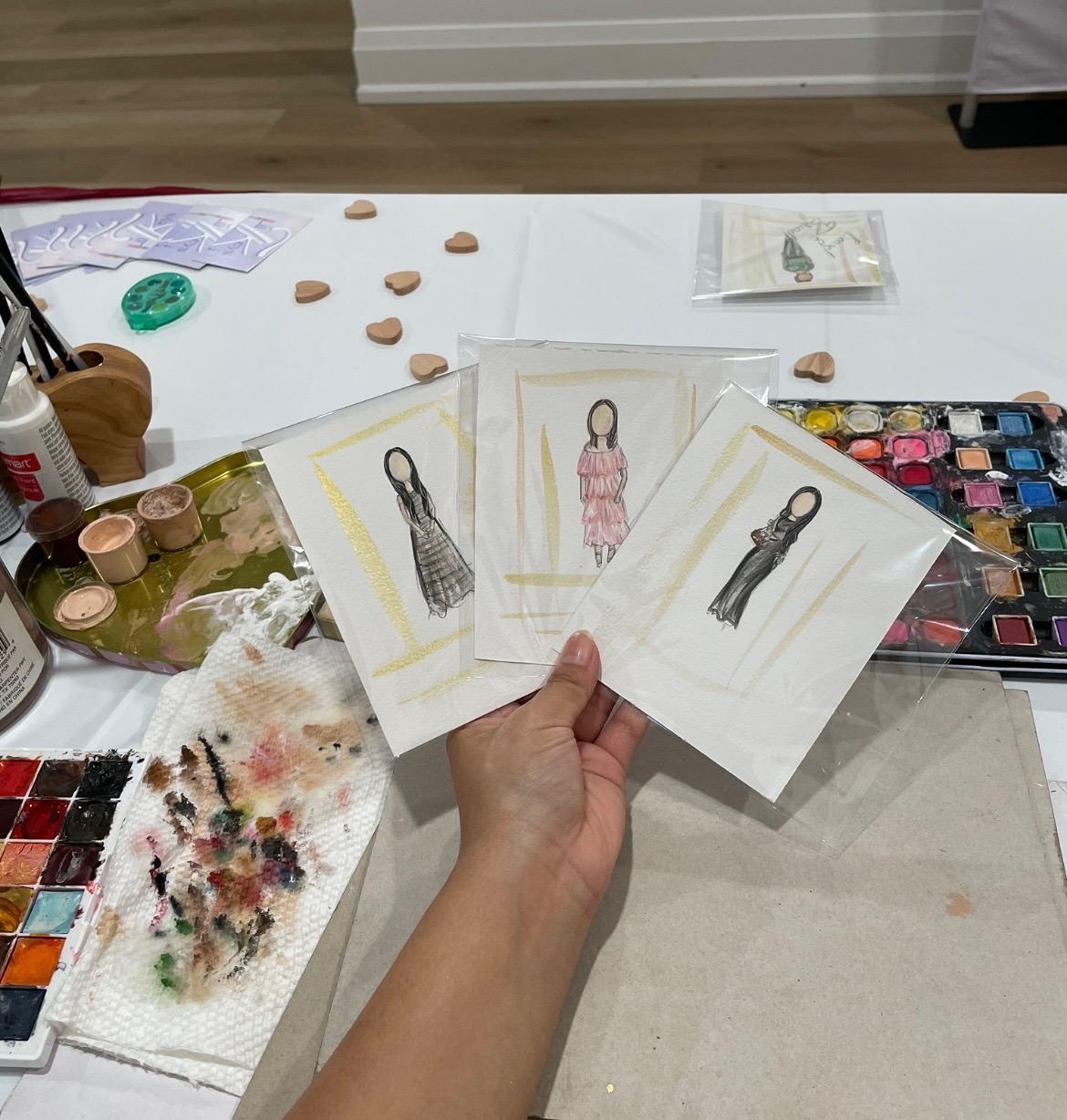 Three finished Lil T Keys Studio guest illustrations on a painting table